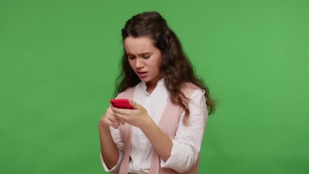 Amazed displeased teenage girl reading message on cell phone, chatting with friends on social networks, dissatisfied with mobile application, using service for online ordering. studio shot, isolated - Filmagem, Vídeo