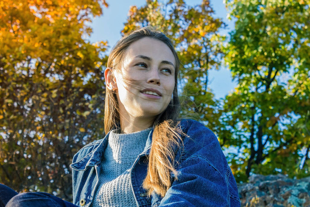 Autumn forest, park, yellow and green foliage. Young modern girl in a denim jacket. Casual style, youth fashion. Positive view of the world, optimism. - Photo, Image