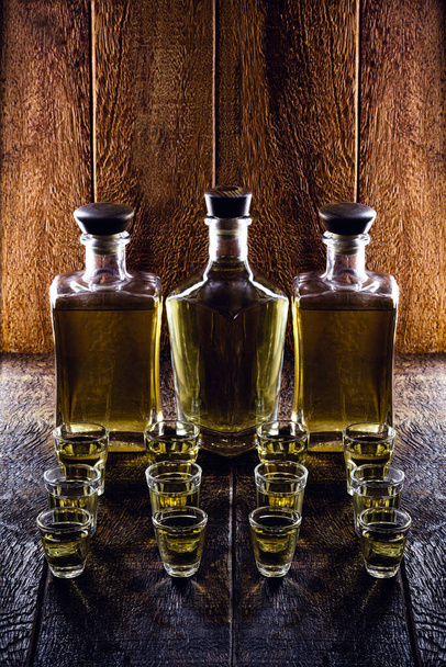 bicchiere di bevanda alcolica, con bottiglia sullo sfondo, ambiente rustico. Cachaca tipo oro brasiliano, chiamato pinga
. - Foto, immagini