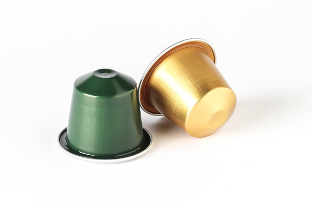vista horizontal de duas cápsulas de café espresso de cor dourada e verde isoladas sobre fundo branco
 - Foto, Imagem