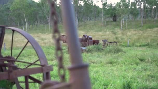 Vieja maquinaria agrícola oxidada en el paddock verde herboso, deslice a la izquierda, luz suave
 - Metraje, vídeo