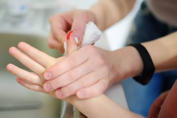 Manos madre aplicando yeso adhesivo médico antibacteriano en el dedo del niño después de herir en casa. Primeros auxilios para niños después de un traumatismo
 - Foto, Imagen