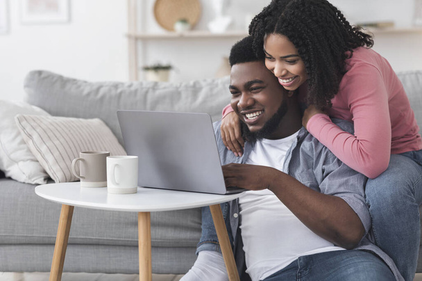 Loving woman embracing her boyfriend that working on laptop at home - Φωτογραφία, εικόνα