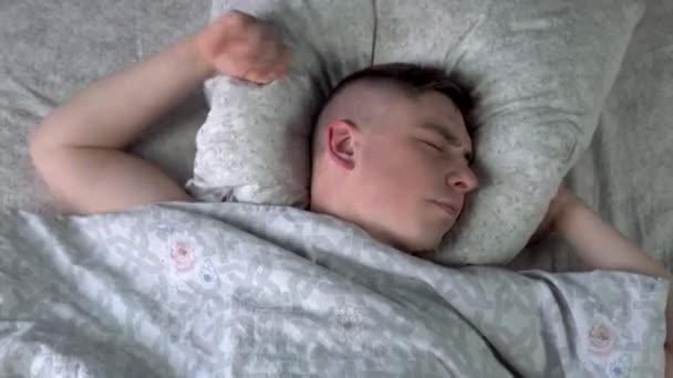 Egy fiatalember nem tud elaludni. Egy férfi fekszik a szobájában az ágyban, és álmatlanságban szenved. Kilátás felülről. - Felvétel, videó