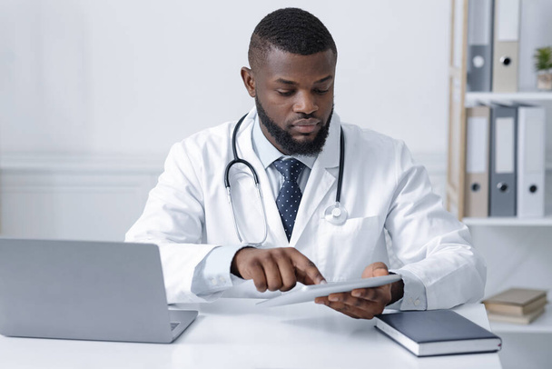 Koncentrált fekete orvos digitális tablettát használ az online konzultációhoz - Fotó, kép