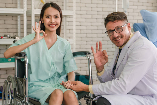 asiatico donna paziente sentirsi felice con visita da caucasico uomo medico a ospedale
 - Foto, immagini