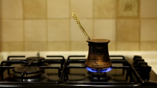 Turkse koffie wordt bereid over een kookplaat, bereikt een kookpunt en morst over de randen. - Video