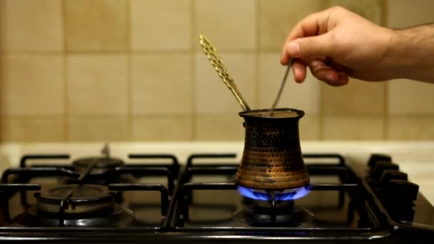 Gemalen zwarte koffie in een koperen Turk wordt gebrouwen en kookt op gasfornuis. Barista het bereiden van warm smakelijk drankje thuis. - Video