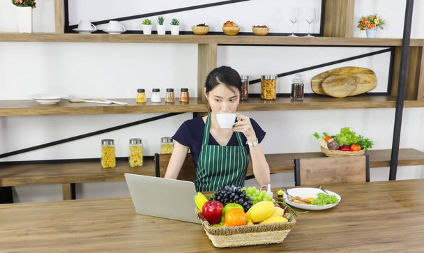 Young Asian entrepreneur or businesswoman work at home by using laptop or computer. Female university student studying e learning online course via webinar. Business and Education concept. - 写真・画像