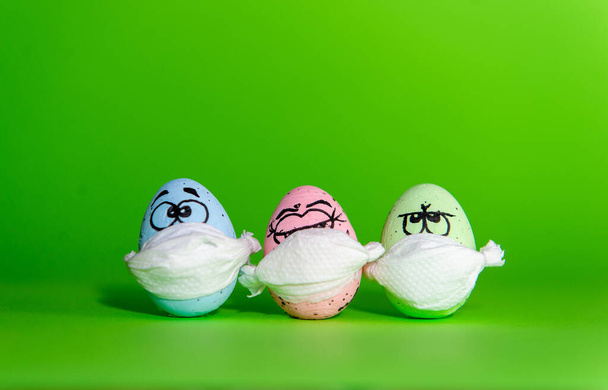 Grappige drie eieren in een masker voor Pasen geïsoleerd op een groene achtergrond - Foto, afbeelding