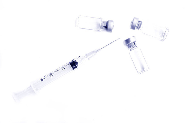 Flacon de médicaments ou vaccin et seringue en plastique de 3 ml avec aiguille isolée sur le fond blanc, couleur bleu
 - Photo, image