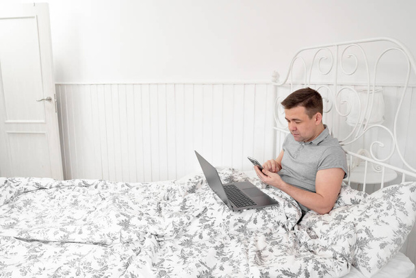 Man freelancer texting on phone in bed isolation - Foto, Imagem