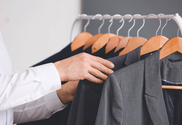 Young male stylist near rack with clothes, closeup - Photo, Image