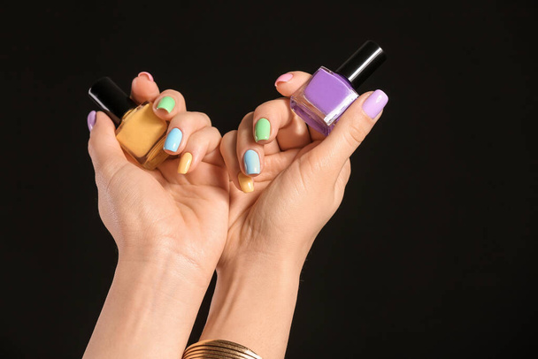 Handen van jonge vrouw met mooie manicure en nagellak op donkere achtergrond - Foto, afbeelding