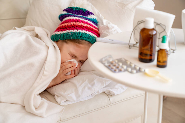 kid girl is sick, has runny nose, colorful hat - Photo, image