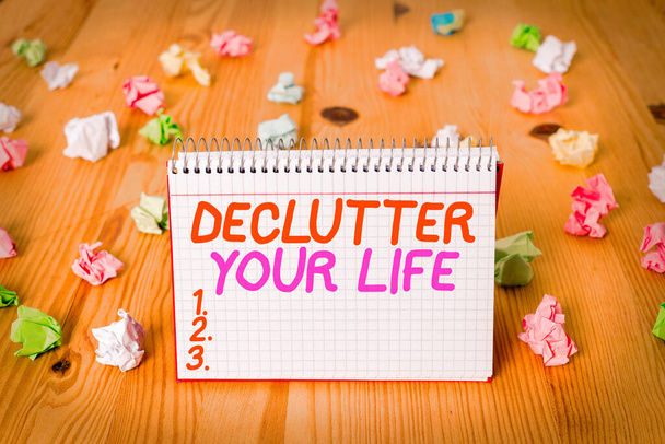 Handwriting text writing Declutter Your Life. Concept meaning To eliminate extraneous things or information in life Colored crumpled papers empty reminder wooden floor spiral notebook office. - Photo, Image