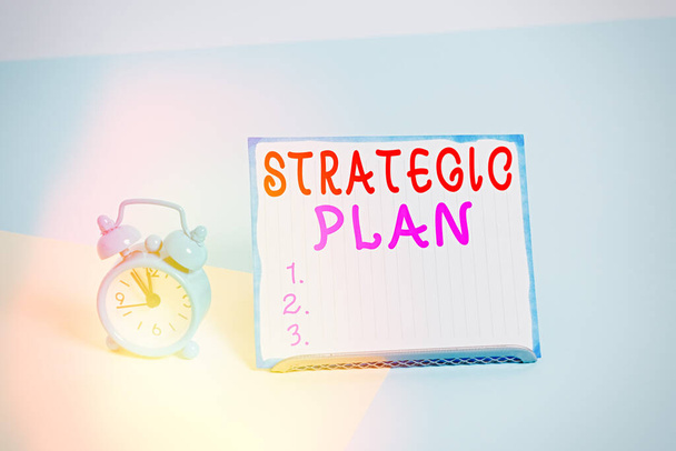 Stratégiai tervet bemutató írásbeli feljegyzés. Üzleti fotó bemutatja a szisztematikus folyamat elképzelése a kívánt jövőbeli ébresztőóra mellett egy papír lap elhelyezett pasztell háttér. - Fotó, kép