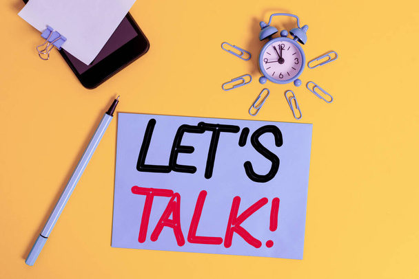 Text sign showing Let Talk. Conceptual photo they are suggesting beginning conversation on specific topic Smartphone clock clips paper sheet notepad ballpoint colored background. - Photo, Image