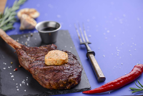 Grillé moyen barbecue rare Steak sur os aux épices servi sur une planche en bois rustique avec sauce sur fond bleu
. - Photo, image