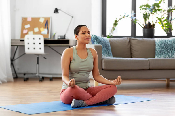woman meditating in yoga lotus pose at home - Photo, image