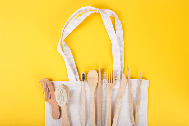 Set of Eco friendly bamboo cutlery on eco bag on yellow backing. Sustainable lifestyle. Plastic free concept. Top view, flat lay, mockup with copy space - Photo, Image