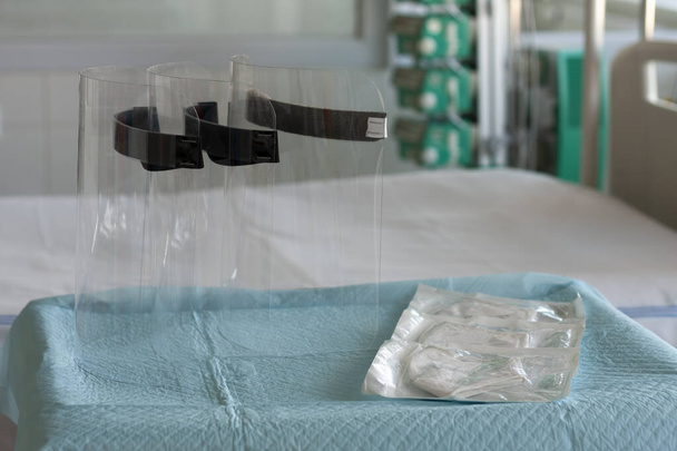 Três escudos de proteção de plástico e três respiradores ffp2 na mesa em UTI no hospital, equipamentos de proteção individual para proteger contra o vírus covid-19
. - Foto, Imagem