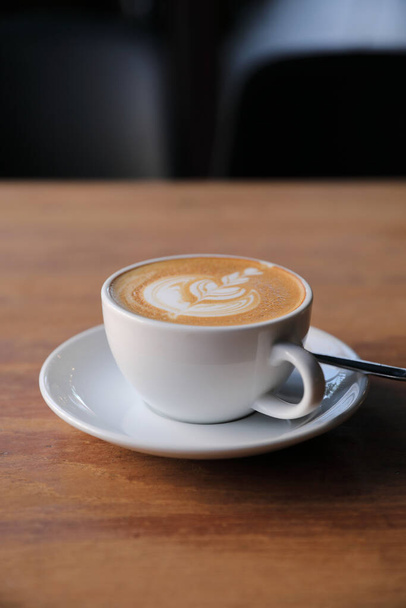 カプチーノかラテかコーヒーショップの木のテーブルの上のミルクから作られたアートコーヒー - 写真・画像