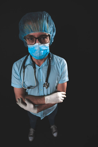Medical doctor, nurse, surgeon, psychologist working with protective mask, glasses and gloves helping people in the days of panic, pandemic - studio shot on black background. - Photo, Image