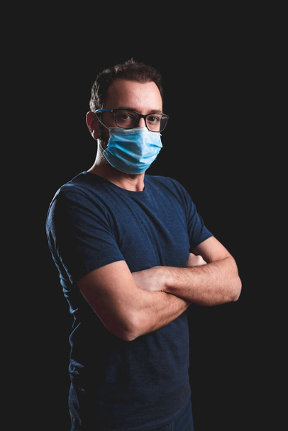 Persona adulta con maschera protettiva che posa su uno sfondo nero - problemi sociali con virus e misure di sicurezza igieniche
. - Foto, immagini