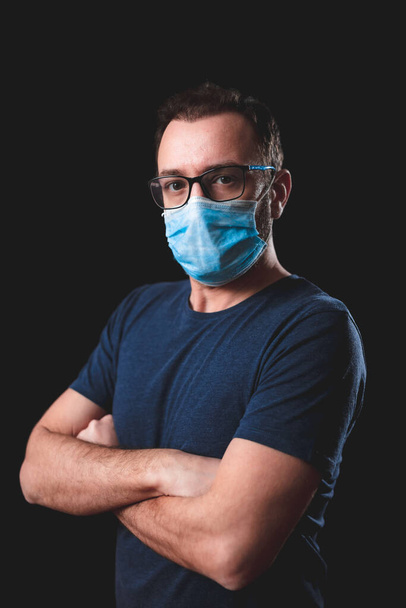 Adulte avec masque protecteur posé sur un fond noir - problèmes sociaux liés au virus et mesures de sécurité en matière d'hygiène
. - Photo, image