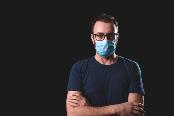 Взрослый человек в защитной маске на черном фоне - социальные проблемы с вирусом и гигиенические меры безопасности
. - Фото, изображение