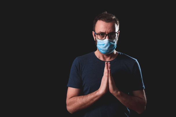 Erwachsene Person mit Schutzmaske posiert auf schwarzem Hintergrund - soziale Probleme mit Virus- und Hygienemaßnahmen. - Foto, Bild