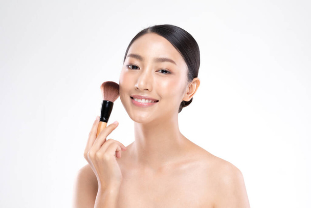 Belle asiatique jeune femme sourire et tenir le pinceau de maquillage avec saine propre et fraîche sensation de peau si bonheur et joyeux, isolé sur fond blanc, Concept de beauté
 - Photo, image