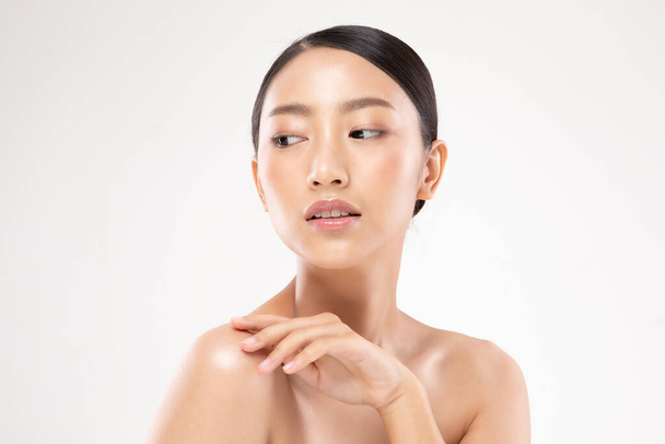 Hermosa mujer asiática joven mirando mientras toca el hombro sintiéndose tan feliz y alegre con una piel sana, limpia y fresca, aislada sobre un fondo blanco, Beauty Cosmetology Concept - Foto, Imagen