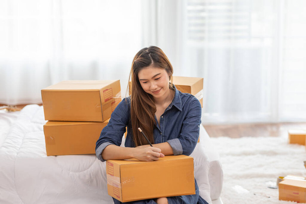 SME entrepreneur of Young women working with laptop and writing customer address for send order Online shopping at home,Cheerful and Happy with box for packaging in home,Startup and Freelance Concept - Foto, Imagen