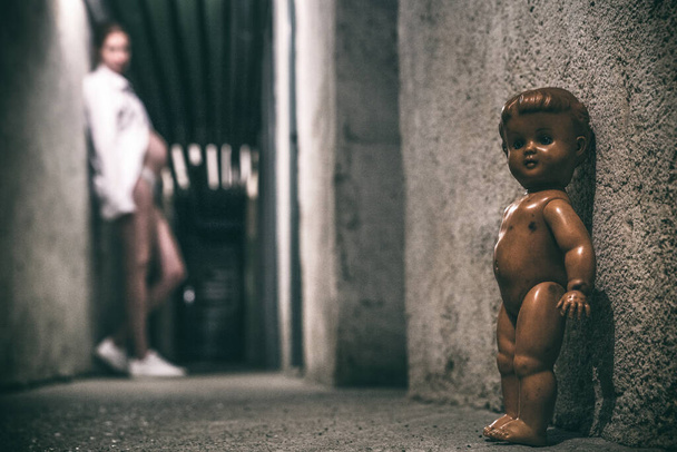 Pregnant girl posing in dark tunnel with old scary doll - Photo, image