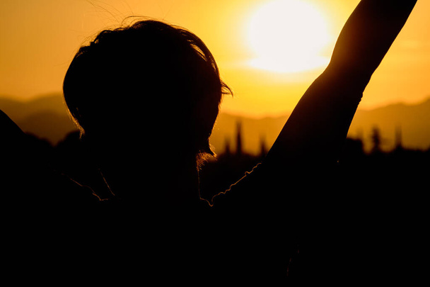 Vrouw met open armen opgeheven bij zonsondergang - Foto, afbeelding