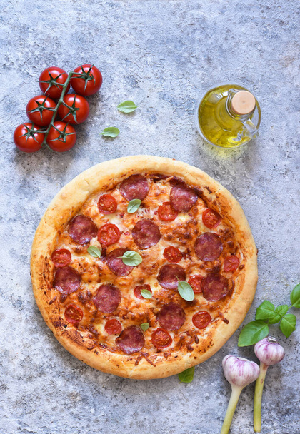 Salami and basil pizza. Pizza on the kitchen table, top view. - Photo, Image