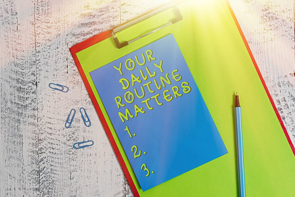 Conceptual hand writing showing Your Daily Routine Matters. Business photo showcasing practice of regularly doing things in fixed order Colored clipboard paper marker sticky note wooden background. - Photo, Image