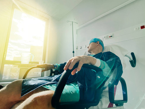 Старший чоловік спить на медичному стільці в сучасній лікарні у Франції. - Фото, зображення