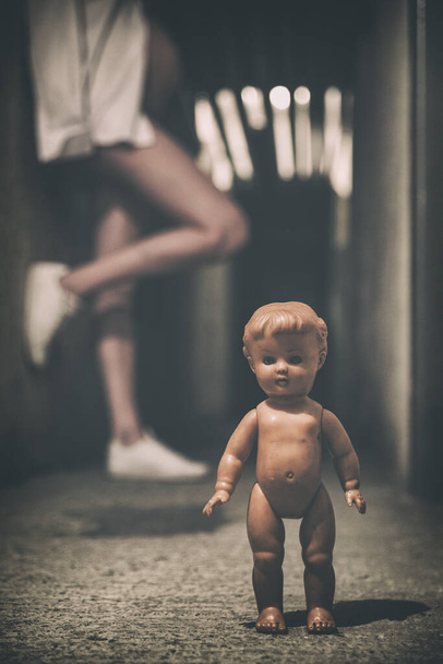 Έγκυος κορίτσι ποζάρουν σε σκοτεινό τούνελ με παλιά τρομακτική κούκλα - Φωτογραφία, εικόνα