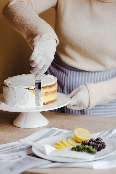 ケーキの上を覆うようにアイシングを広げていた主婦。へらを使って表面を滑らかにし、切り取られた写真を閉じます。隔離の自由時間. - 写真・画像