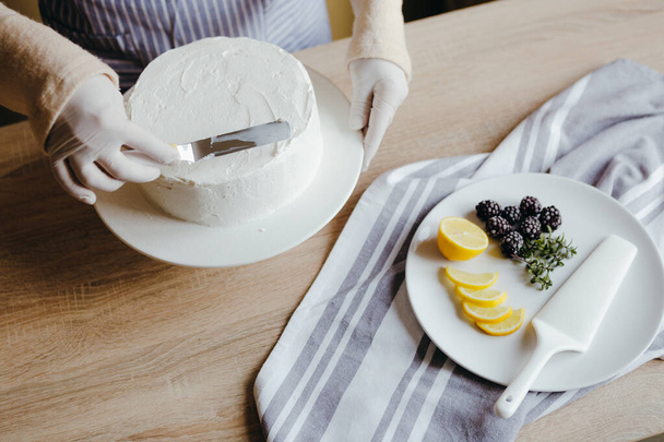 Ev hanımı ev yapımı limonlu kek pişiriyor. İnsan elinin üstünde bıçakla hamur işi pişirmekle meşgul.. - Fotoğraf, Görsel