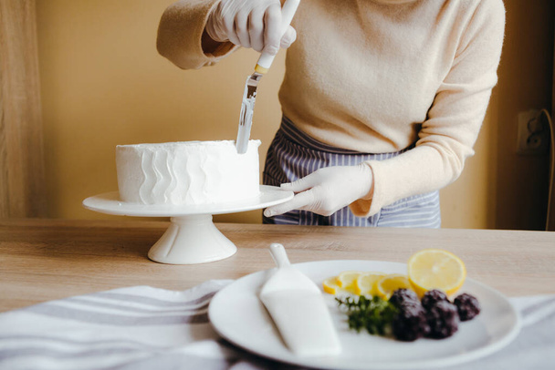 Kotiäiti laittaa kotitekoista sitruunakakkua. Edellä näkymä ihmisen kädet kiireinen leivonnaiset ruoanlaitto veitsellä
. - Valokuva, kuva