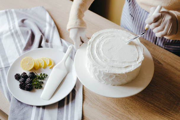 主婦が自家製レモンケーキを作っている。ナイフを使ったペストリー料理で忙しい人間の手の上のビュー. - 写真・画像