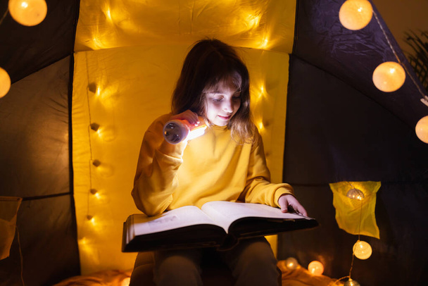 Młoda dziewczyna student nauki i wychowania domowego w domu wykonane namiot z świecące kulki świetlne. - Zdjęcie, obraz