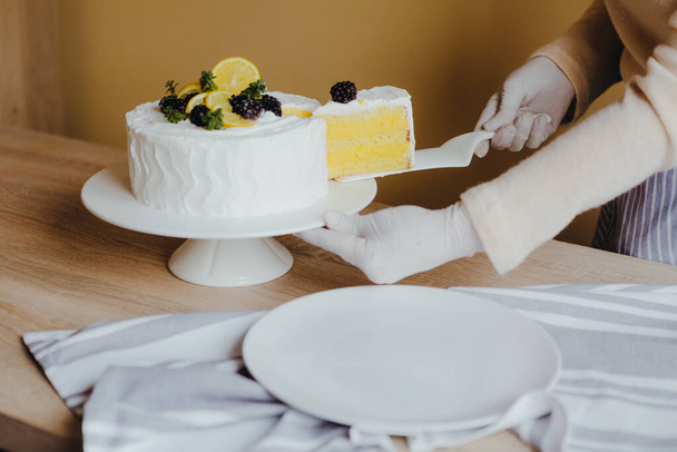 Femme au foyer prenant une tranche de gâteau au citron frais délicieux anniversaire maison à la table, vue de dessus. Recette de gâteau au citron bio
. - Photo, image