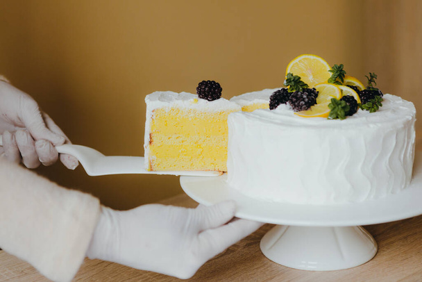 Housewife taking slice of fresh delicious birthday homemade lemon cake at table, top view. Recipe of lemon organic cake. - Photo, Image