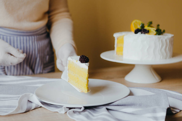 Домохозяйка берет кусочек свежего вкусного домашнего лимонного торта за столом, вид сверху. Рецепт лимонного органического торта
. - Фото, изображение