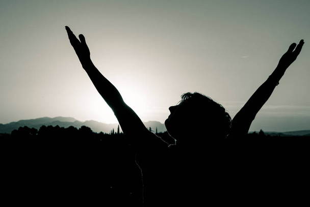 Жінка з відкритими руками, піднятими на заході сонця
 - Фото, зображення